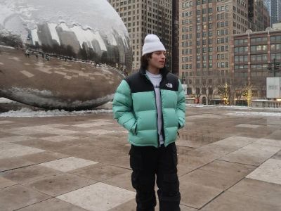 Christopher Sturniolo is wearing the north face jacket and a white cap with The Bean in the background.